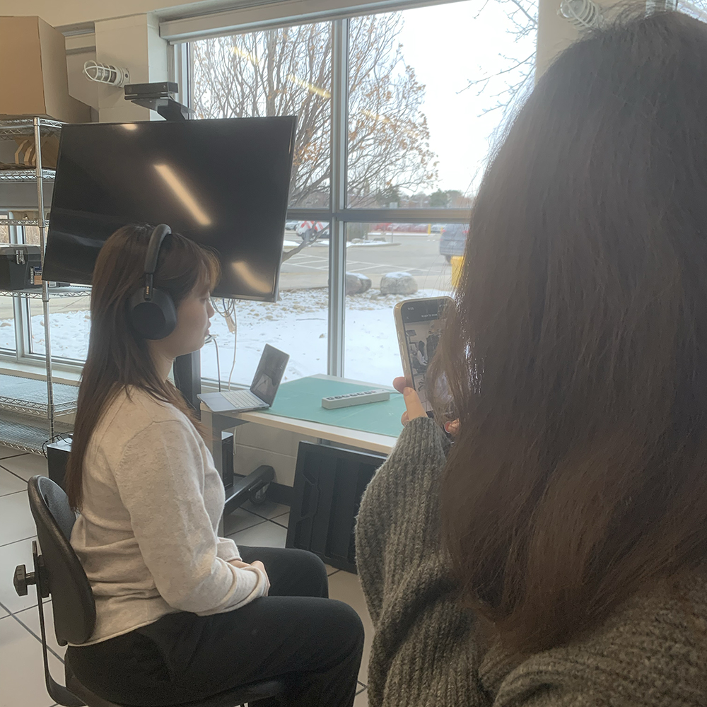 <b>Starting the Scanning Process</b><br>Here, my classmate begins scanning me with the ScanViewer app while I sit wearing headphones. I’m positioned in front of a computer monitor in our lab, getting ready for the scanning process.