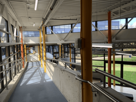 <b>Indoor Ramp with Bright Beams</b><br>This photo, which I took on Sheridan campus, shows an indoor accessibility ramp. It was originally built to provide easy access between different floors of the building. Today, it remains an essential feature for ensuring all students, especially those with mobility needs, can move freely and safely.