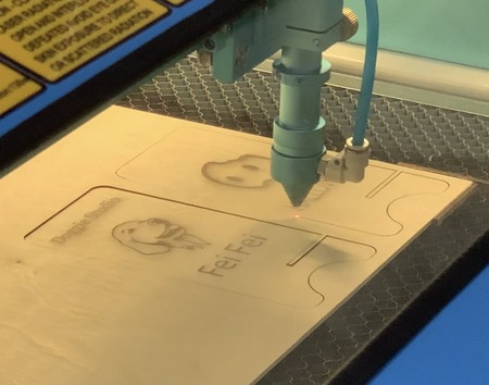 <b>Laser Cutting Process at Sheridan - Detail</b><br>
          Here, the laser cutter continues to carve out the design and outline of the phone stand. It’s carefully cutting the ghost and name, as well as the stand’s shape, into the wood.
