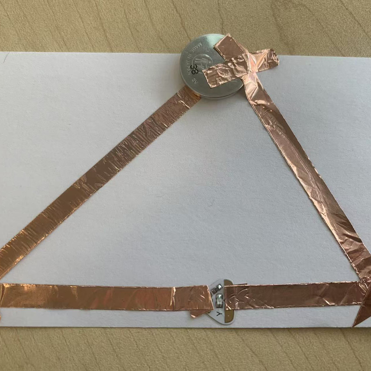 I tested the triangular circuit by pressing the connections. The LED lit up with an orange glow, confirming the circuit works.