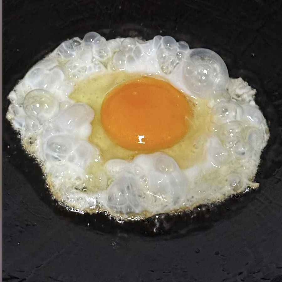 A sunny side up egg frying in a pan, capturing the sizzle of the egg as it cooks.