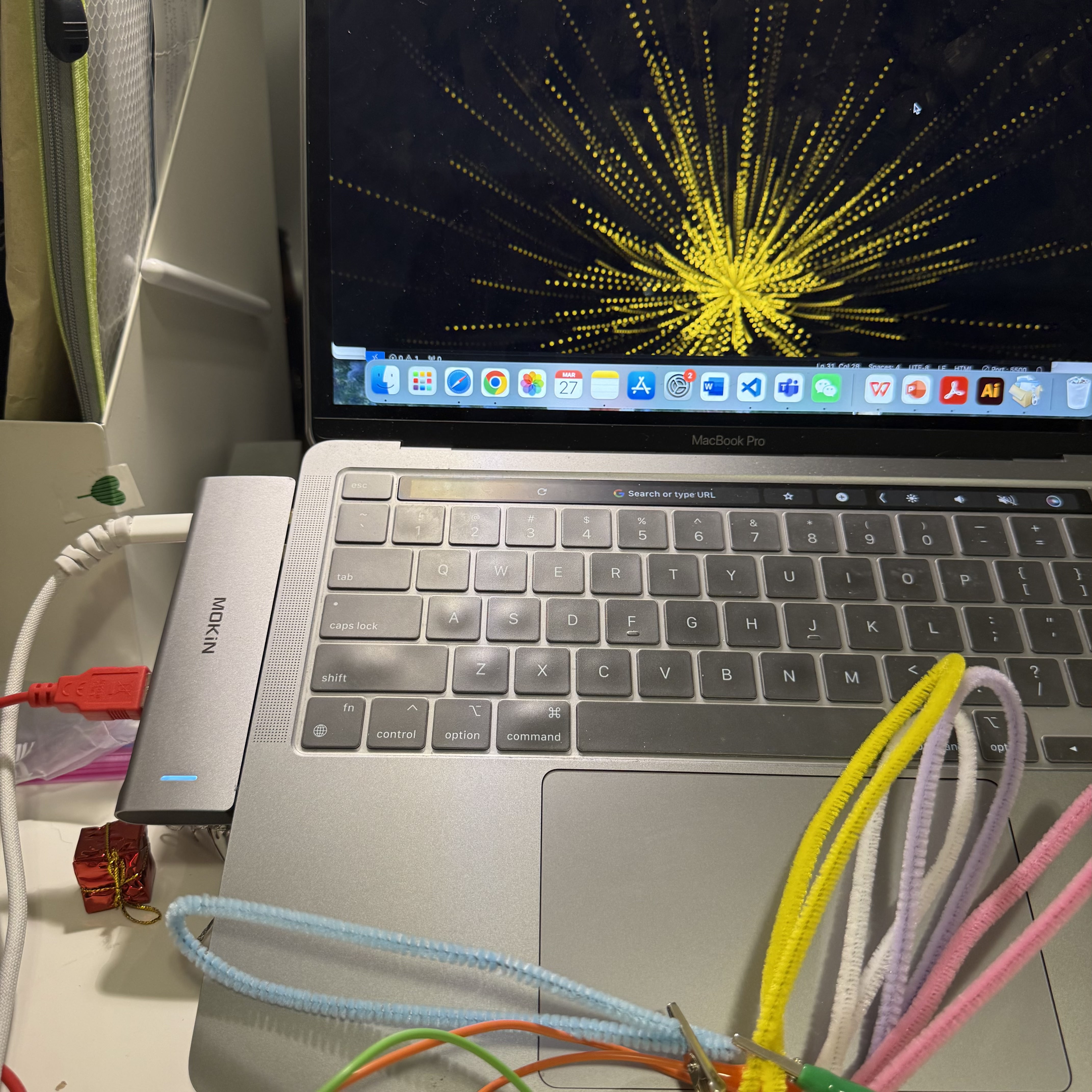  I am actively using the pipe cleaners attached to the Makey Makey board to interact with my laptop. Touching these colorful elements causes changes in the digital animations displayed on my screen, highlighting how simple materials can become effective tools for digital interaction.